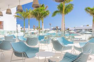 a patio with blue chairs and palm trees at Hotel Lava Beach in Puerto del Carmen