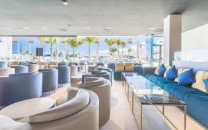 a lobby with couches and tables and palm trees at Hotel Lava Beach in Puerto del Carmen