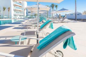 a row of chairs and umbrellas next to a pool at Hotel Lava Beach in Puerto del Carmen