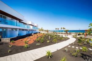 a building with a lot of plants in front of the ocean at Hotel Lava Beach in Puerto del Carmen