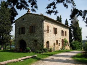 un antiguo edificio de piedra con una carretera delante de él en Agriturismo Il Caio, en Cetona