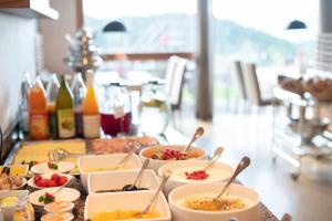 uma mesa coberta com tigelas de comida com colheres em Hotel am Hang em Soprabolzano