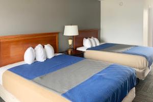 Pokój hotelowy z 2 łóżkami z biało-niebieskimi poduszkami w obiekcie Lakeview Inn w mieście Lake Saint Louis