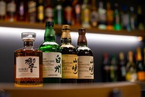 un gruppo di bottiglie di whisky seduti su uno scaffale di Tanakaya Kyoto Karasuma a Kyoto