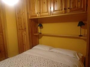 a bedroom with a white bed and wooden cabinets at Casa Grande in Pragelato