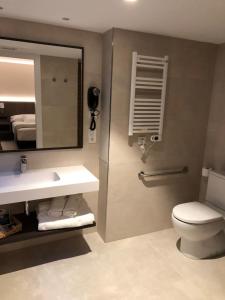 a bathroom with a sink and a toilet and a mirror at Hotel Balneario de La Virgen in Jaraba