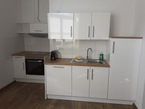 uma cozinha com armários brancos e um lavatório em Ferienwohnung Angelika em Wilhelmshaven