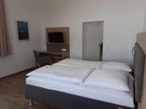 um quarto com uma cama com lençóis brancos e uma secretária em Ferienwohnung Angelika em Wilhelmshaven