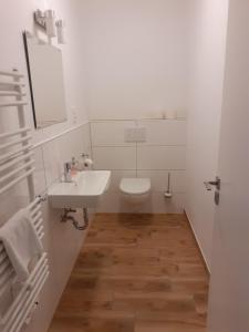 Baño blanco con lavabo y aseo en Ferienwohnung Diana, en Wilhelmshaven
