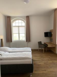 1 dormitorio con 2 camas, ventana y escritorio en Ferienwohnung Diana, en Wilhelmshaven