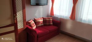 a red couch with pillows sitting in a room at Hermina Panzió in Siófok