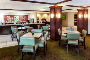 a restaurant with tables and chairs and a bar at La Quinta by Wyndham Milwaukee Bayshore Area in Glendale