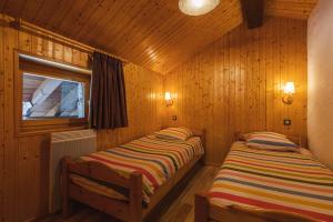 two beds in a room with wooden walls at L'arpont in Champagny-en-Vanoise