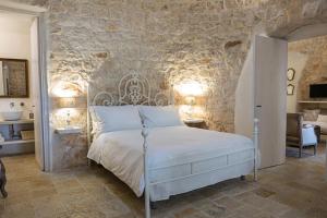 een slaapkamer met een bed en een stenen muur bij Borgo Fantese in Ostuni +30 foto's