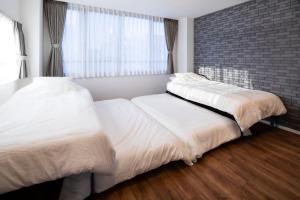 2 camas en un dormitorio con una pared de ladrillo en HOTEL LITTLE BIRD OKU-ASAKUSA / Vacation STAY 79448 en Tokio