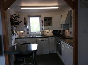 a kitchen with white cabinets and a sink and a window at Anstey Cove in Bembridge