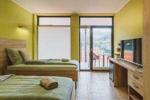 a bedroom with two beds and a television and a balcony at Center Vintgar in Slovenska Bistrica