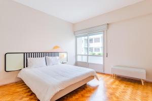 um quarto branco com uma cama grande e uma janela em AMAZING DUPLEX - Mid Century Experience & PARKING no Porto
