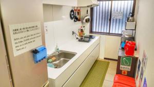 a small kitchen with a sink and a refrigerator at ゲストハウス栞庵 in Kyoto