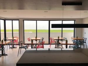 NAIM Hotel في كابيتوليو: غرفة طعام مع طاولات وكراسي ونوافذ