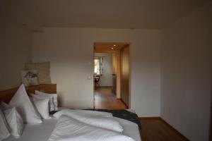 a bedroom with a bed with white sheets and a hallway at Bucherhof in Obsteig