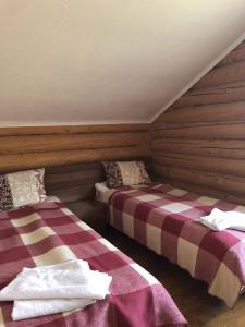 two beds in a room with wooden walls at Золото Карпат in Izki