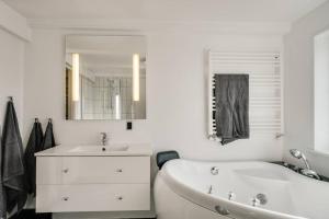 ein Badezimmer mit einem Waschbecken, einer Badewanne und einem Spiegel in der Unterkunft Marieshus in Holstebro