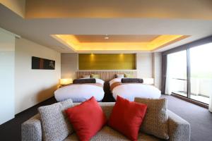 a hotel room with two beds and a couch with red pillows at Hotel Regina Kawaguchiko in Fujikawaguchiko