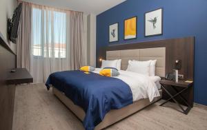 sypialnia z dużym łóżkiem z niebieską ścianą w obiekcie voco - Podgorica, an IHG Hotel w mieście Podgorica