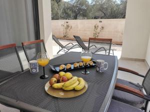 un tavolo con un piatto di frutta e due bicchieri di succo d'arancia di Villa Prova M a Jezera