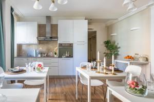 Momo Central Rome 2 في روما: مطبخ بدولاب بيضاء وطاولات بيضاء وكراسي