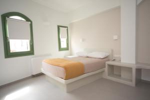 a white bedroom with a bed and two windows at Pelican Hotel in Fira