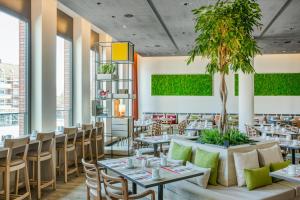 a restaurant with tables and chairs and plants at IntercityHotel Hamburg-Barmbek in Hamburg