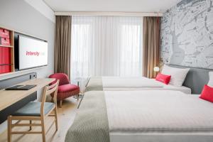 a hotel room with two beds and a desk at IntercityHotel Hamburg-Barmbek in Hamburg