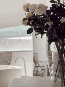 un jarrón lleno de rosas blancas sentadas en una mesa en La Maga Rooms, en Xàtiva