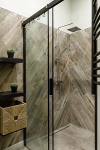 a shower with a glass door with wood at Roomburg Apartments in Saint Petersburg
