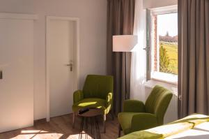 um quarto com 2 cadeiras verdes e uma janela em Lindenhof Hotel Garni em Sulsdorf auf Fehmarn