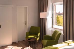 1 dormitorio con 2 sillas verdes y una ventana en Lindenhof Hotel Garni en Sulsdorf auf Fehmarn