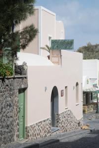 a white building with a green door on a street at Pelican Hotel in Fira
