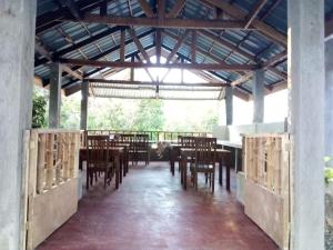 Balai Mariacaria Pension House في Guindulman: غرفة طعام بطاولات وكراسي في جناح
