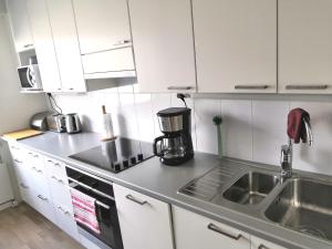 uma cozinha com armários brancos e um lavatório em City Apartment Savonkatu em Kuopio