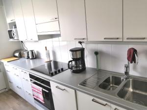 a kitchen with white cabinets and a sink at City Apartment Savonkatu in Kuopio +11 photos