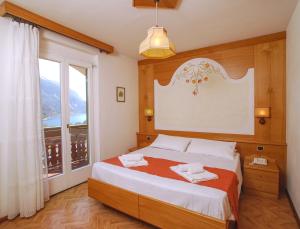 a bedroom with a bed and a large window at Charme Hotel Nevada in Molveno