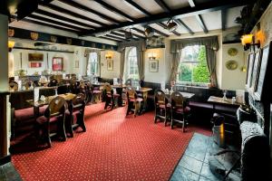 a restaurant with tables and chairs on a red carpet at The Queens Head Kettlesing in Harrogate