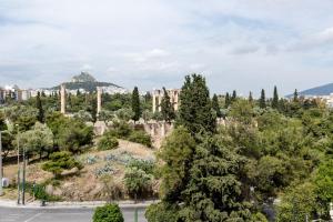 einen Blick auf die Akropolis von Athenen mit Bäumen und Gebäuden in der Unterkunft Parthenon Apartment in Athen