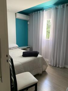1 dormitorio con 2 camas, silla y ventana en Mello's House, en Curitiba