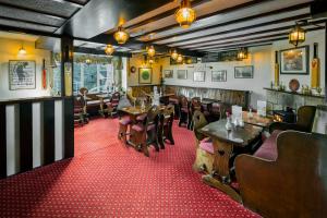 un restaurante con mesas y sillas de madera y alfombra roja en The Queens Head Kettlesing, en Harrogate