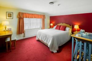 a bedroom with a bed and a red wall at The Queens Head Kettlesing in Harrogate