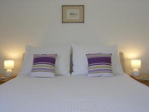 1 cama blanca con 2 almohadas y 2 lámparas en Apartments GORDANA Baska for relaxing holidays, en Baška
