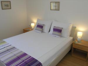 1 dormitorio con 1 cama blanca grande y 2 lámparas en Apartments GORDANA Baska for relaxing holidays, en Baška
